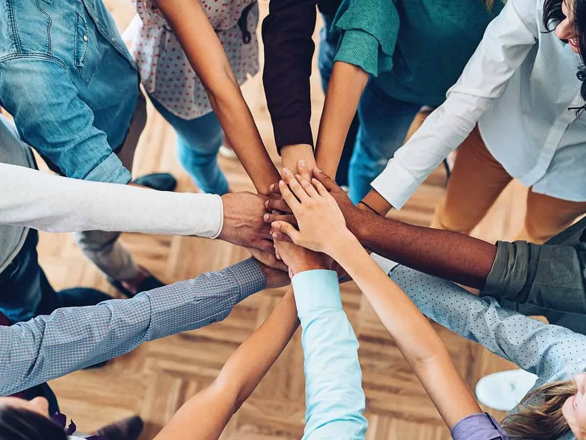 Les mains d’une équipe réunies en cercle : créer du lien au travail